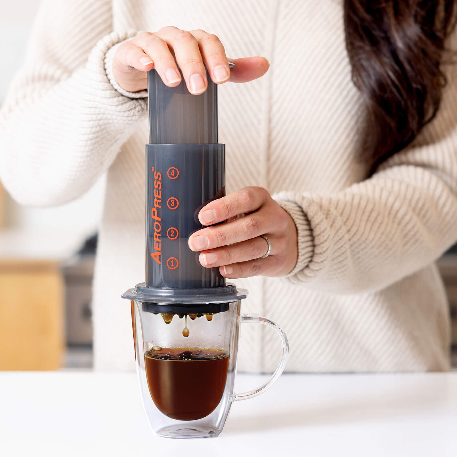 person making aeropress coffee into clear mug