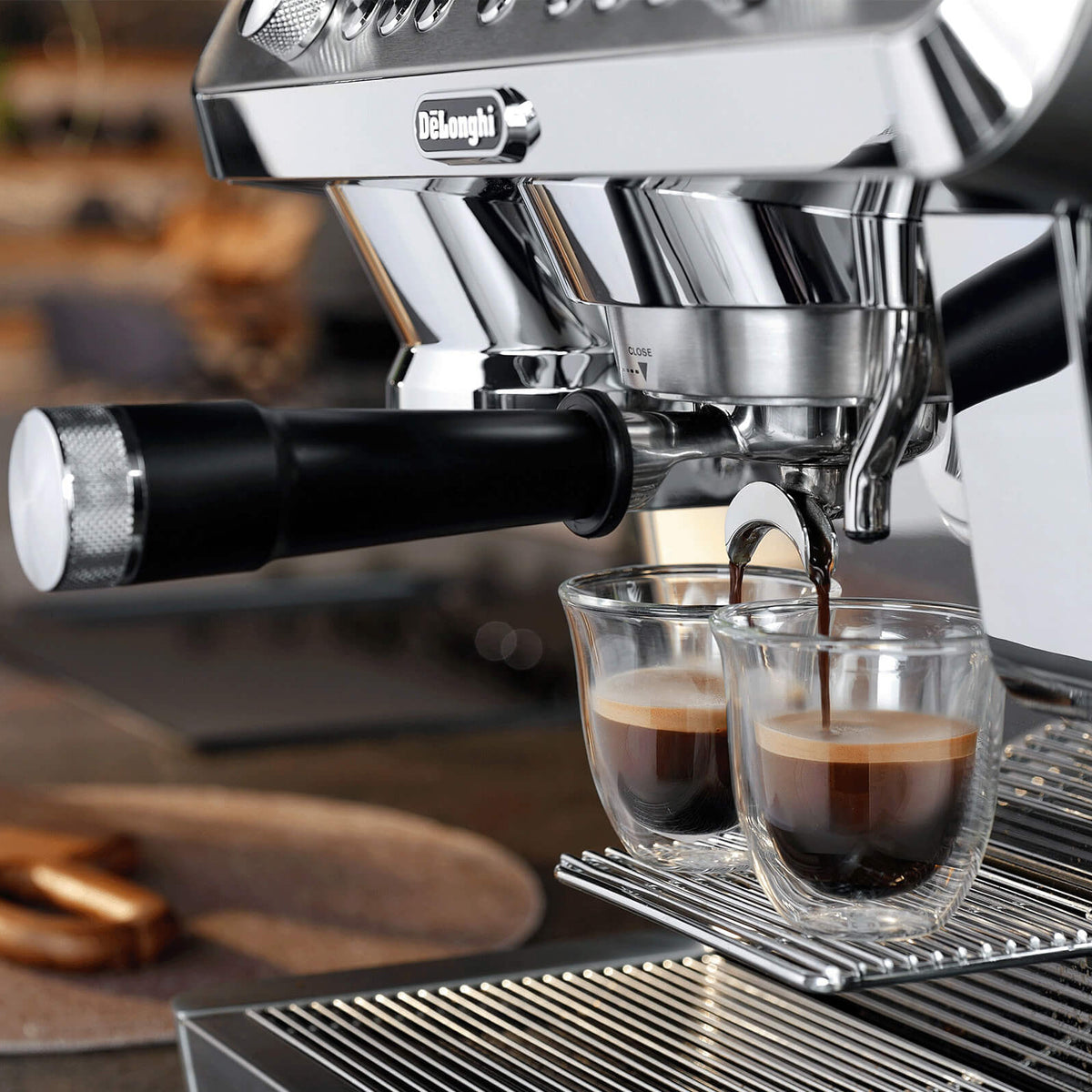 Espresso machine pouring coffee into two glasses on a kitchen counter.