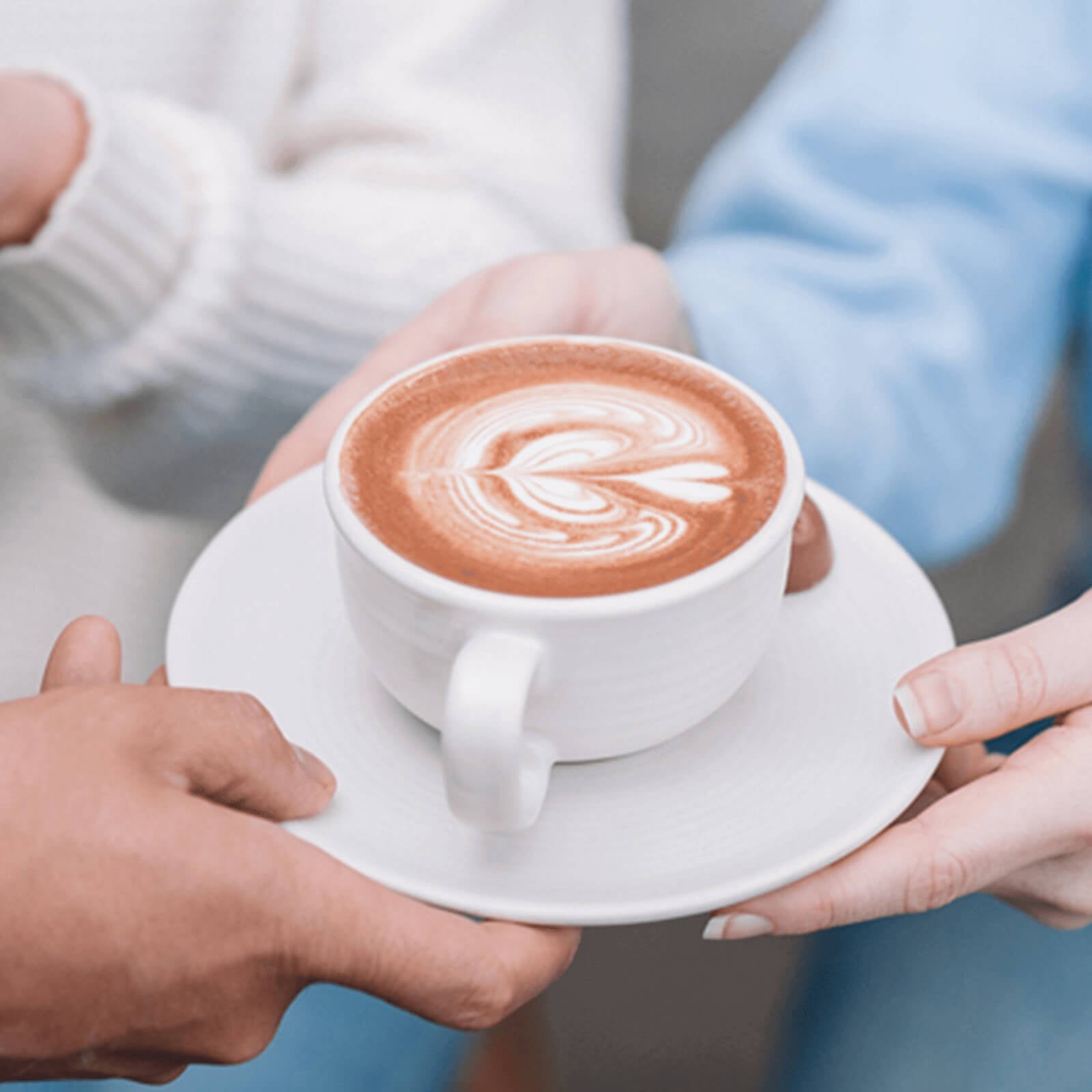 Two people exchanging a cup of cappuccino