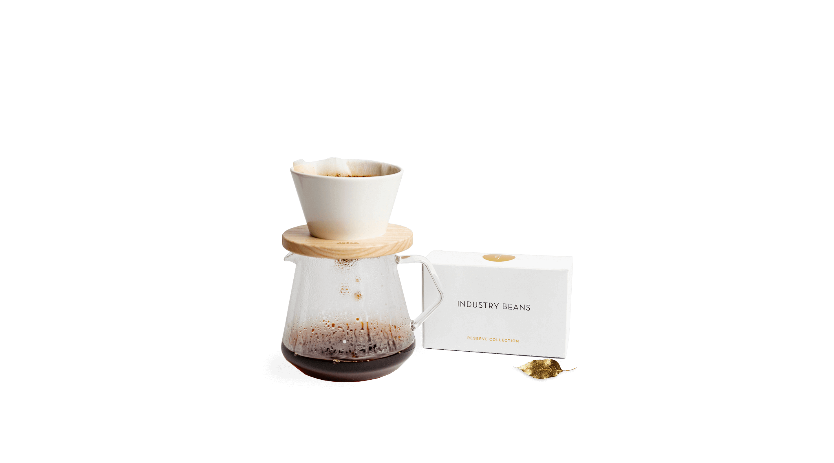 Coffee brewing setup with a glass carafe and wooden lid, accompanied by a white box of coffee beans.