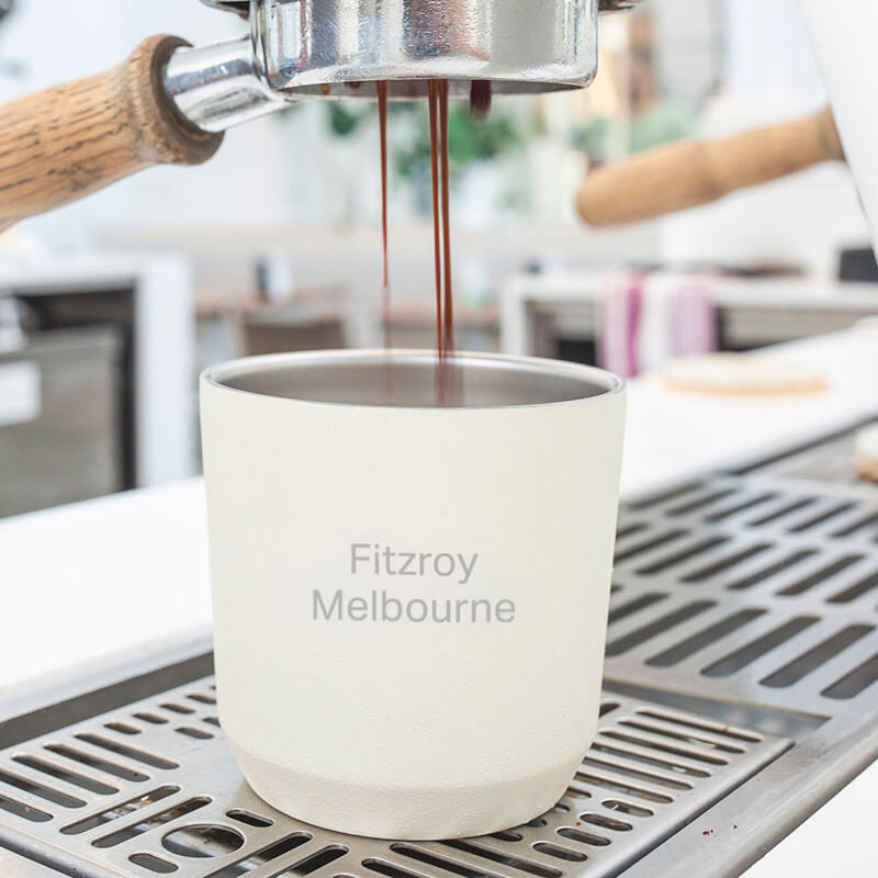 Espresso being poured into a Kinto Reusable Coffee Cup labeled 'Fitzroy Melbourne' on a coffee machine.