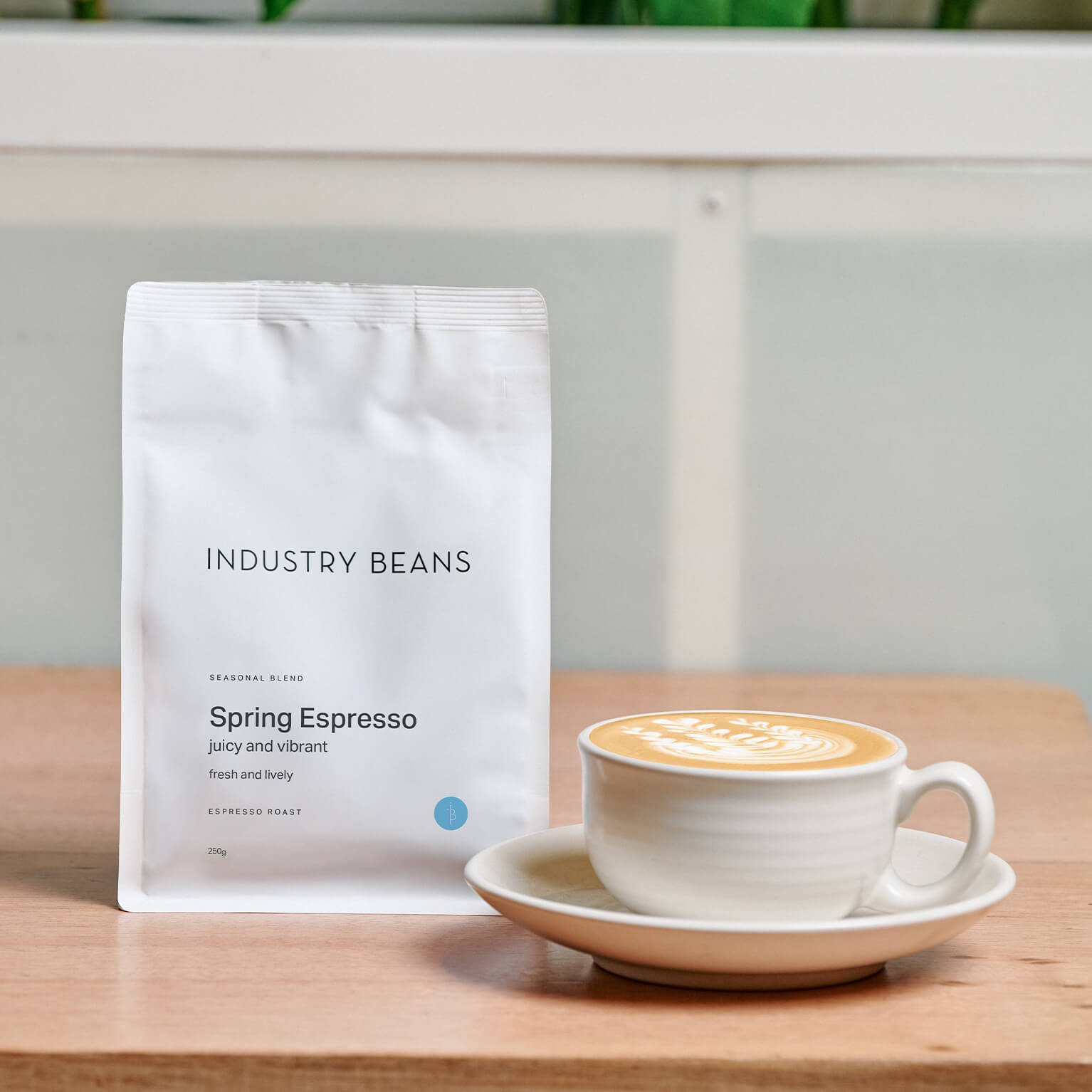 A 250g bag of industry beans spring espresso with a flat white