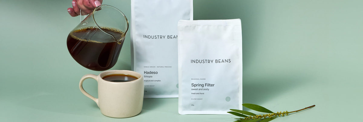 Bag of Industry Beans Autumn Filter Blend on sandstone block with glass mug of filter coffee