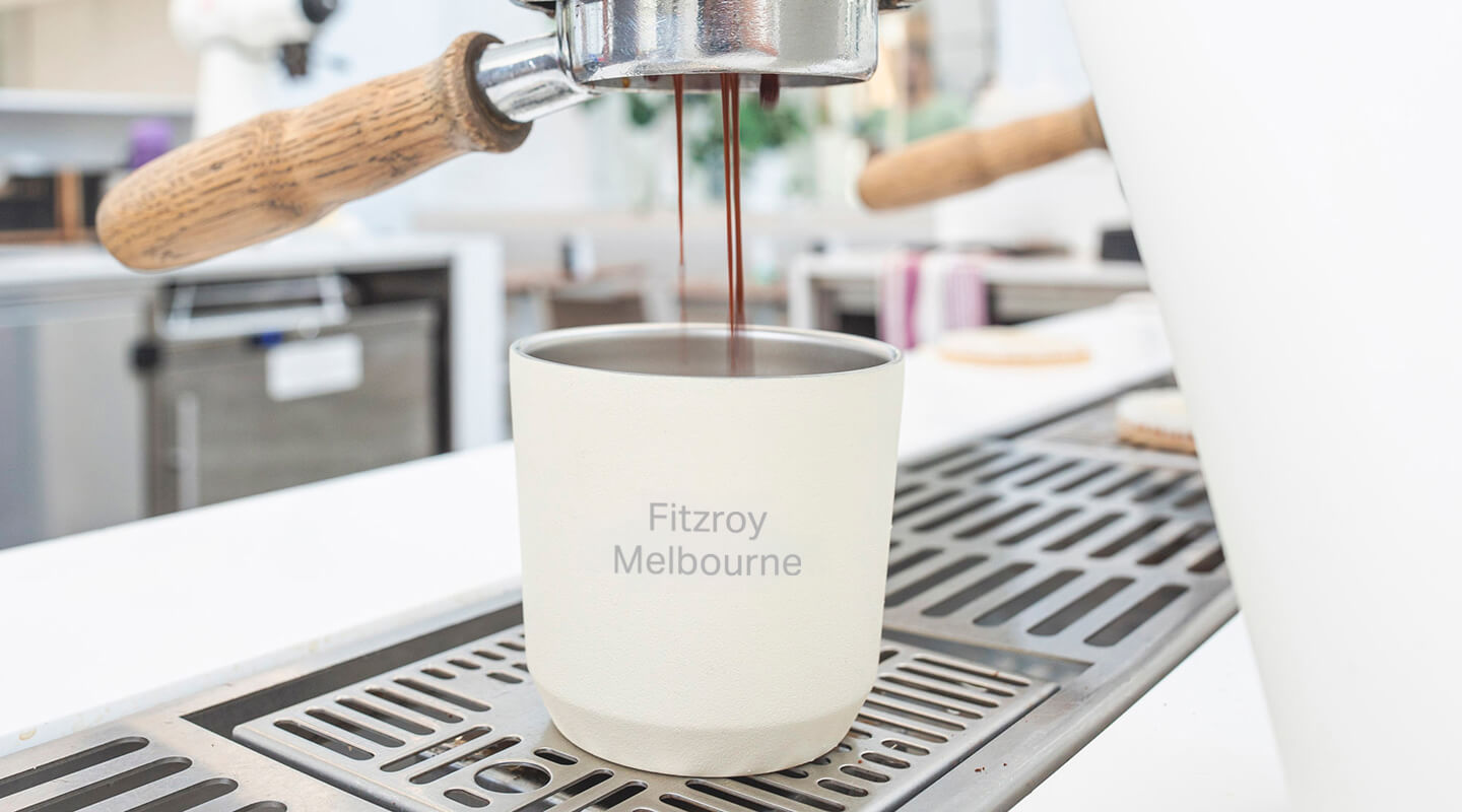 Espresso being poured into a Kinto Reusable Coffee Cup labeled 'Fitzroy Melbourne' on a coffee machine.