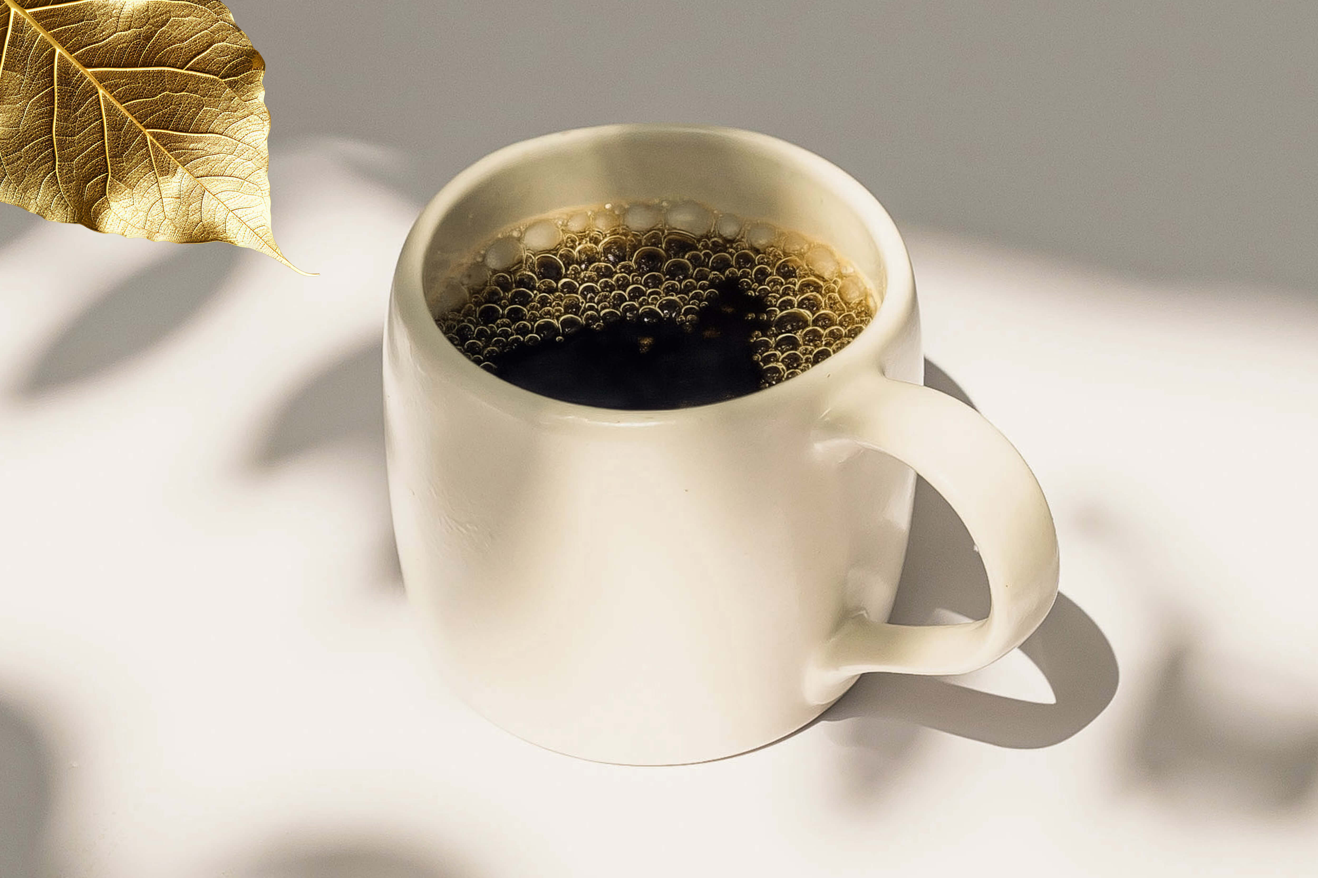 White batch brew mug with Industry Beans Reserve Collection coffee on a light surface with a gold leaf