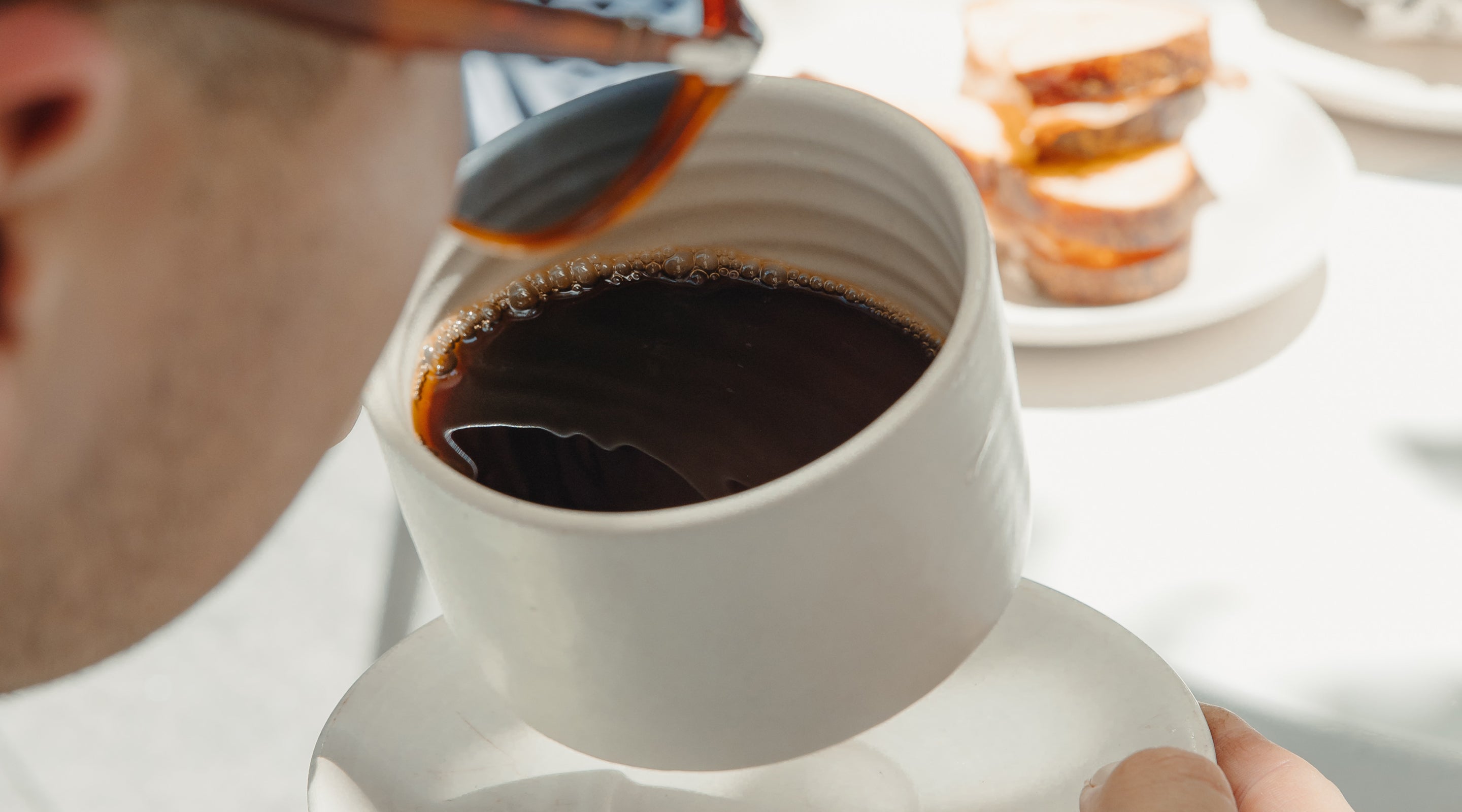 Person taking sip from white ceramic mug of Industry Beans Filter Single Origin coffee