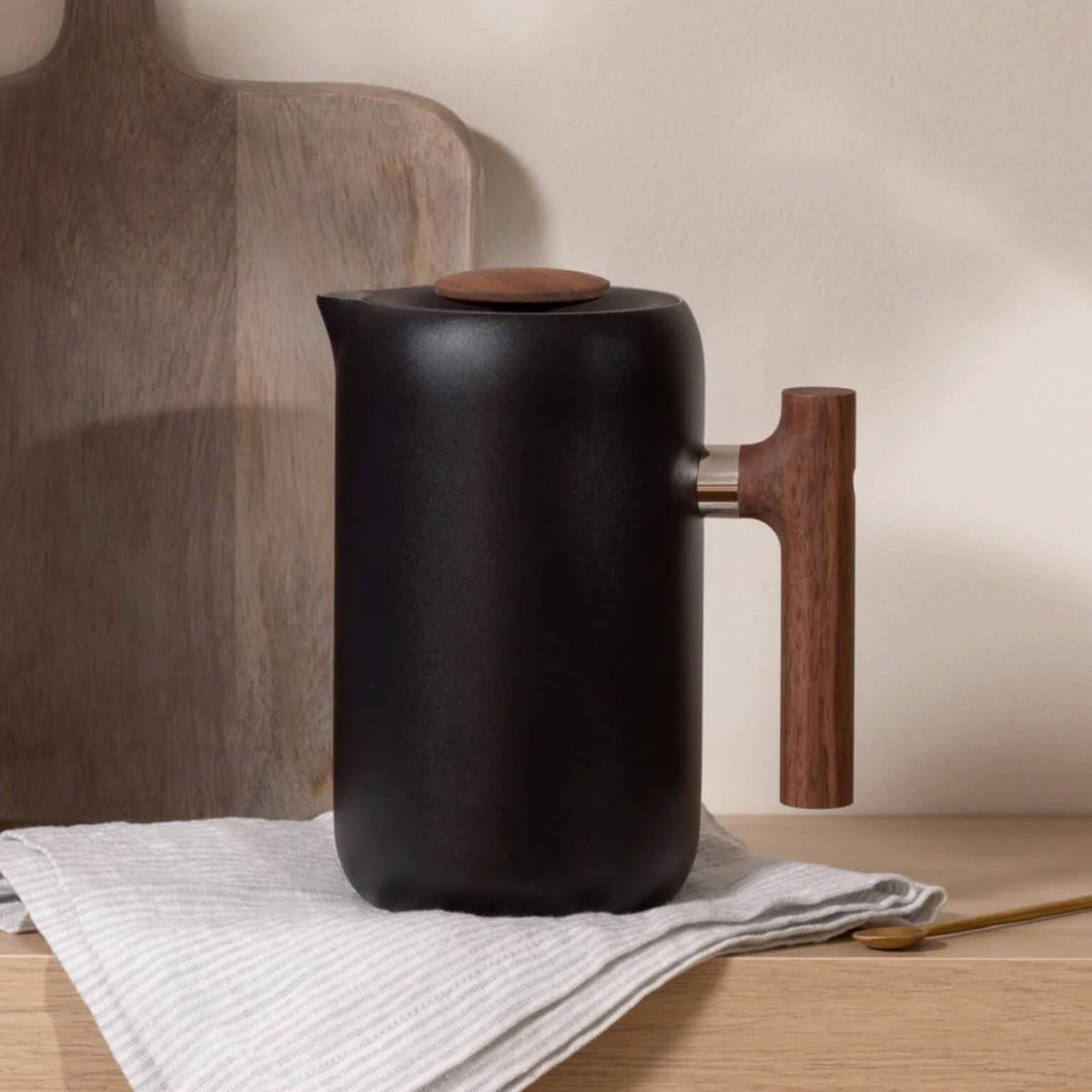 Black Fellow Clara French Press with walnut handle on a kitchen wooden bench