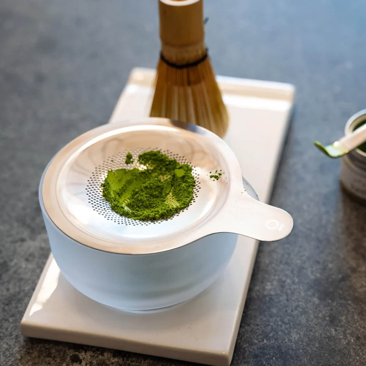 Fellow Matcha Set in Matte White with matcha powder on the sifter, angled view