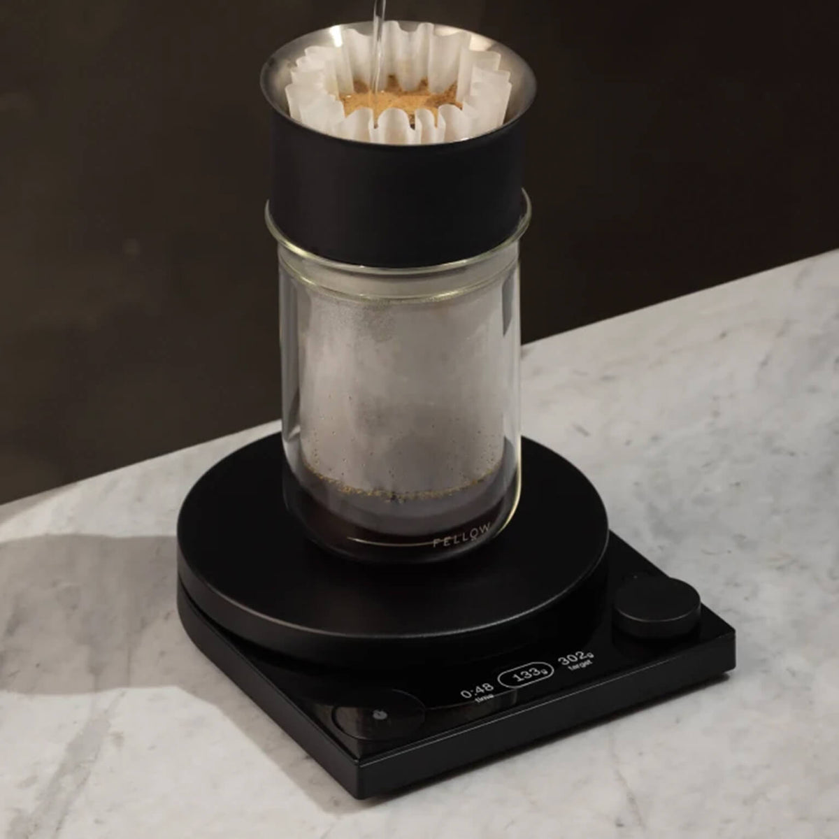 Fellow Tally Pro Precision Scale in Matte Black weighing a pour-over brew into a Stagg Tasting Glass
