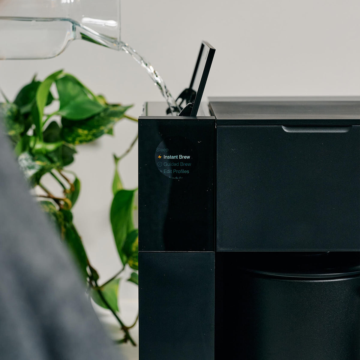Water being poured into a black Fellow Aiden coffee maker