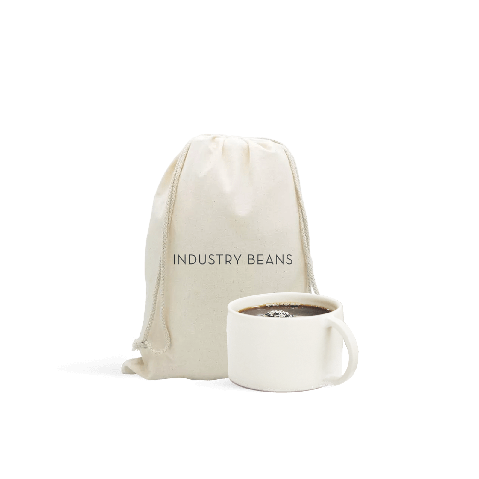 A white ceramic mug with a wide bottom, sitting next to a calico gift bag with 'INDUSTRY BEANS' printed on it.