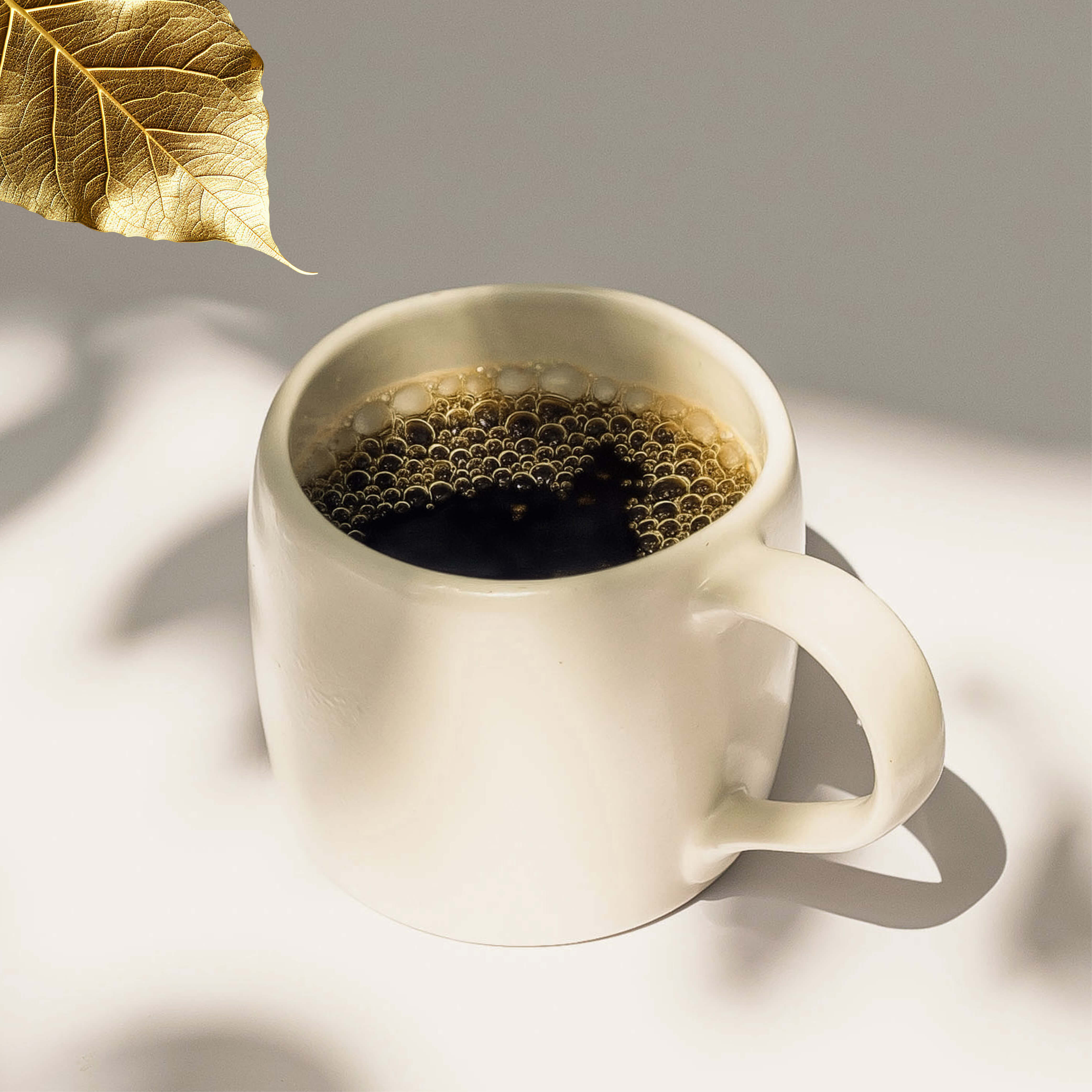 White batch brew mug with Industry Beans Reserve Collection coffee on a light surface with a gold leaf