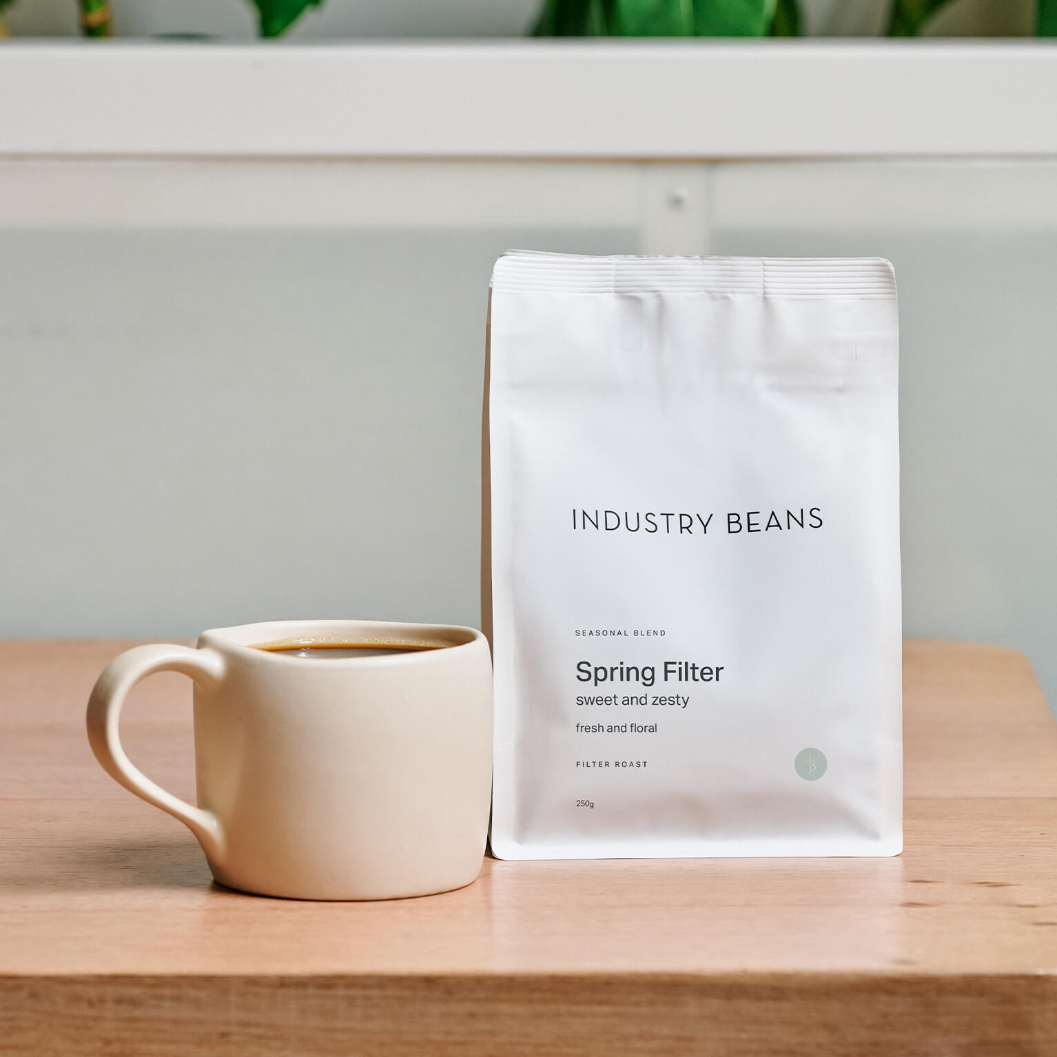 A 250g bag of spring filter blend with a batch brew mug of black coffee